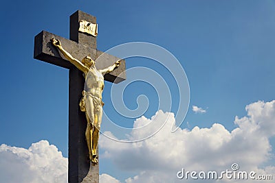 Golden Jesus Christ crucifixion statue, sunny summer day blue sky background Stock Photo