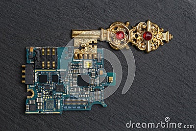 golden key connected to a microchip board, on a black stone texture. Stock Photo