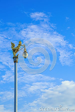 Golden Kinnaree on light pole against blue sky Stock Photo