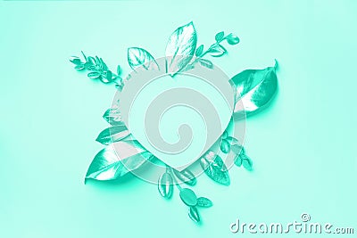 Golden leaves, heart shaped paper on mint background with copy space. Top view. Trendy green and turquoise color. Creative design Stock Photo