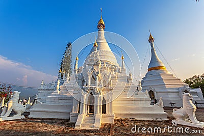Golden light shining on white and gold pagoda during sunrise / sunset with blue sky Stock Photo