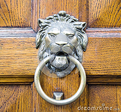 Golden lion head knocker on an old wooden door Stock Photo