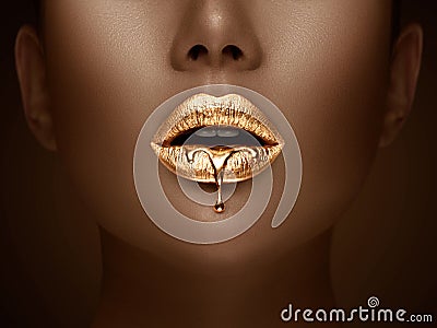 Golden lipstick closeup. Liquid metal dripping from gold lips. Beautiful makeup. Sexy lips, bright liquid paint on girl`s mouth Stock Photo