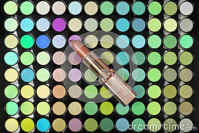 Golden lipstick on colorful eyeshadow palette background. Flat lay Stock Photo