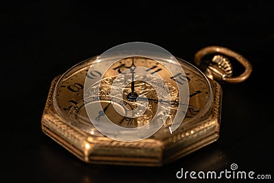 Golden mechanical antique pocket watch lying on black surface. Retro pocketwatch with second, minute and hour hand. Old Stock Photo