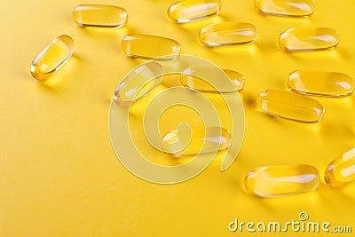 Golden omega capsules on yellow background closeup Stock Photo