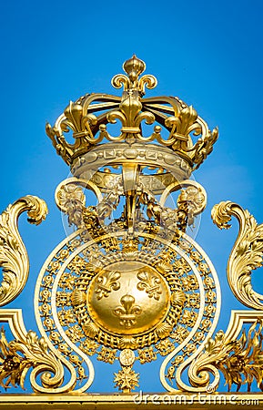 Golden ornate gate crown of Chateau de Versailles on blue sky background. Paris, France, Stock Photo