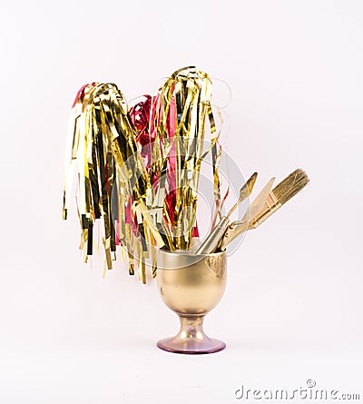 Golden party whistles with stripes, spatula and brush gathered in a golden glass Stock Photo