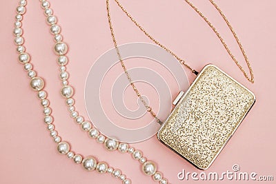 Golden purse and pearl necklace on pink background Stock Photo