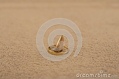 A golden ring slung over a bullet in the sand Stock Photo