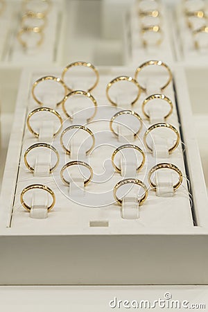 golden rings store. Wedding gold rings on the showcase. Wedding ring set. toned. vertical photo Stock Photo