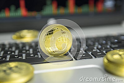 Golden Ripple coin with gold coins lying around on a black keyboard of silver laptop and diagram chart graph on a screen Editorial Stock Photo