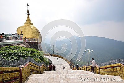Golden rock on left and large stairs on right with hilly mountainous view in the background at Kyaiktiyo Pagoda Editorial Stock Photo