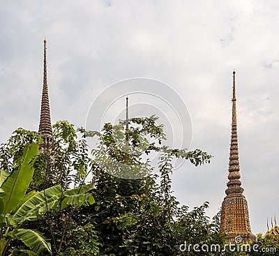 Golden spires of the Wat Pho temple revealed behind lush greenery in Bangkok, Thailand Stock Photo