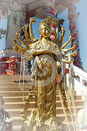 Beautiful Golden Thousand-hand Guan Yin statue stands in front of the pavilion Stock Photo