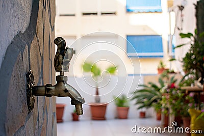 Gold-colored water tap on terrace in the shape of a squirrel. Outdoor yellow animal-shaped water tap in the garden. Stock Photo