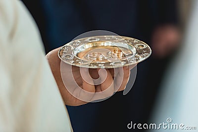 Golden wedding rings on a golden plate in the hands of a priest in the church Stock Photo