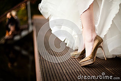 Golden wedding shoes from white dressed bride Stock Photo