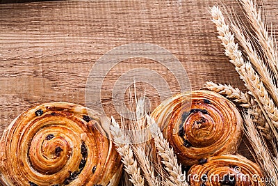 Golden wheat ears sweet raisin rolls on oaken Stock Photo