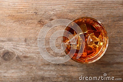 Golden whiskey in glass with ice cubes on wooden table, top view. Stock Photo