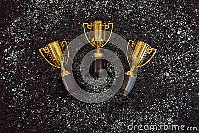 Golden winner cups with silver sparkles on a black background. Stock Photo