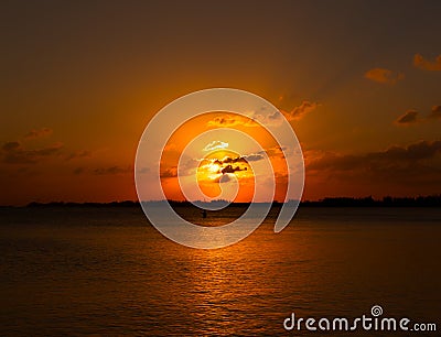 Golden yellow sunset over the sea ocean water with clouds and sun in the sky and reflection in the water with fisherman Stock Photo