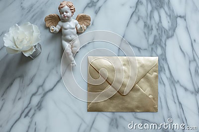 goldleaf envelope on marble with cupid figurine Stock Photo