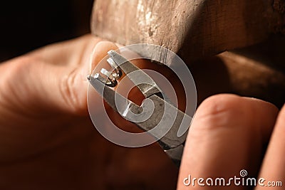 goldsmith hands working on a silver wire spiral with pliers small chain rings, macro shot with copy space Stock Photo