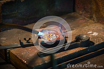 Goldsmith melting gold and silver granules in a crucible with a Stock Photo