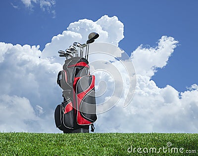 Golf clubs on grass with blue sky and clouds Stock Photo