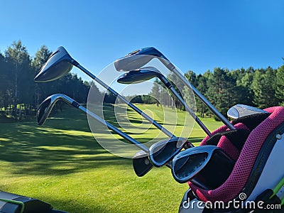 Golf clubs resting in a bag with a lush green fairway Stock Photo