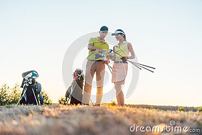 Golf instructor teaching a young woman how to use different golf clubs Stock Photo
