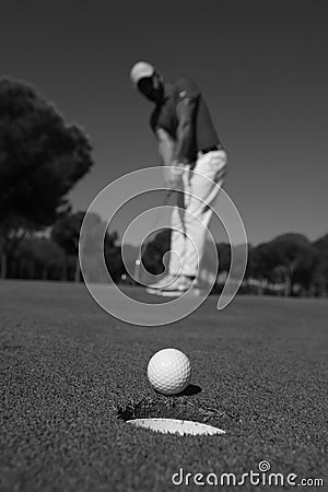 Golf player hitting shot, ball on edge of hole Stock Photo