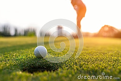 Golfer asian woman putting golf ball on the green golf on sun set evening time, select focus. Stock Photo