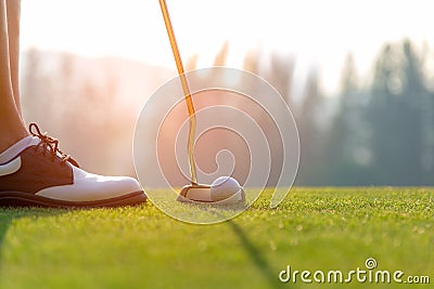 Golfer asian woman putting golf ball on the green golf on sun set evening time. Stock Photo