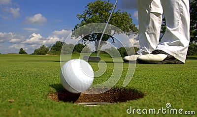 Golfer putting ball into hole Stock Photo