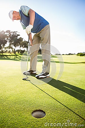 Golfer standing on the putting green watching hole Stock Photo