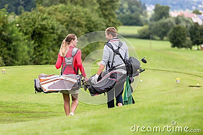 Golfing couple walking and chatting on golf course Stock Photo