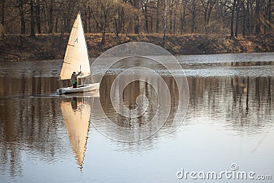 GOMEL, BELARUS - 9 April 2017: A small boat with a sail swims along the river in the spring Editorial Stock Photo