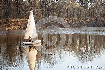GOMEL, BELARUS - 9 April 2017: A small boat with a sail swims along the river in the spring Editorial Stock Photo
