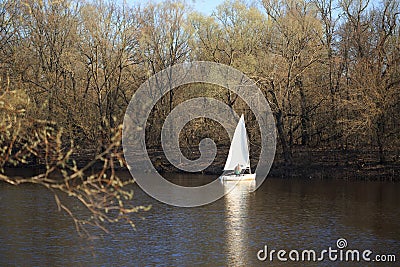 GOMEL, BELARUS - 9 April 2017: A small boat with a sail swims along the river in the spring Editorial Stock Photo