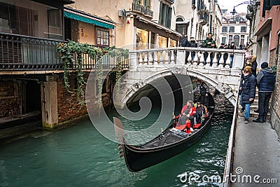 Gondola flows under the bridge at the narrow canal in Venice, Italy Editorial Stock Photo