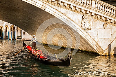 Gondola passing under the Rialto Bridge at sunset in Venice, Italy Editorial Stock Photo