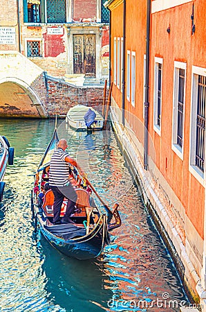 Gondolier on gondola with tourists people sailing in narrow water canal in Venice Editorial Stock Photo