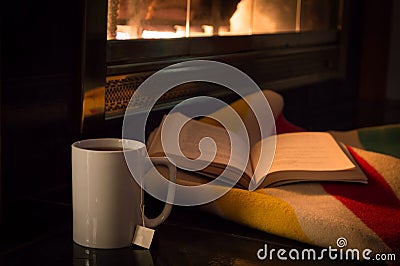 A good book and a cup of tea by a cozy fire. Stock Photo