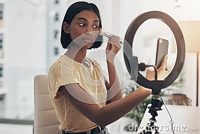 With a good brush comes good makeup. a young woman applying makeup while filming a beauty tutorial at home. Stock Photo