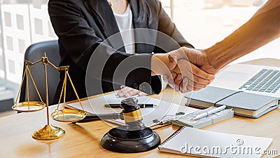 After a good cooperation, a consultation between a male lawyer and a businessman client with a hammer and golden scales on the tab Stock Photo