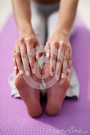 Good health is made up of small goals. a young woman touching her toes while practicing yoga outside on a sunny day. Stock Photo