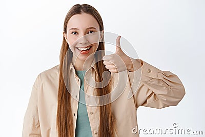 Good job, very well. Smiling teenage girl shows thumbs up and say yes, nod in approval, praise excellent choice Stock Photo