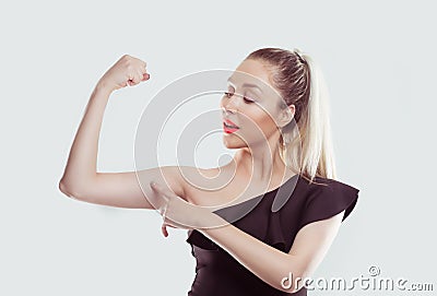 Good, look, my muscles are growing. Young happy woman flexing muscles showing her strength isolated white light blue wall Stock Photo